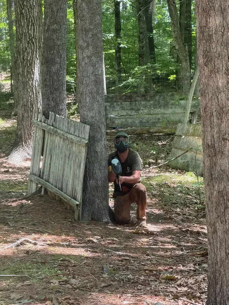 Masked player uses a tree and wooden cover on the Woods field